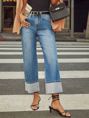 Light wash denim jeans with wide legs and large cuffed hems.