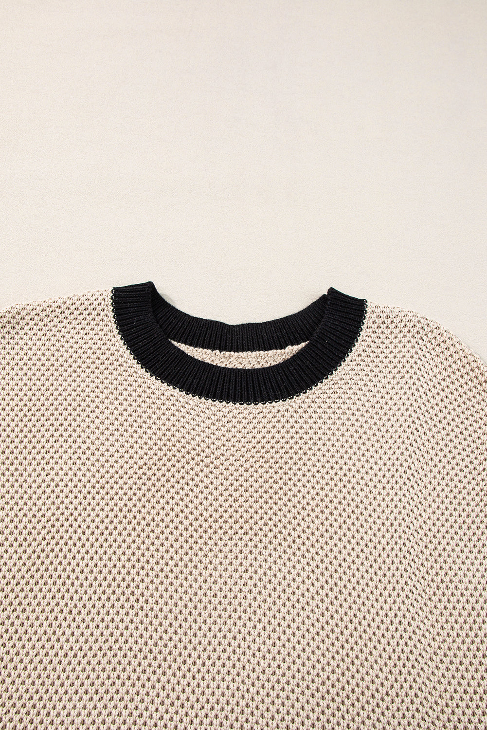 Beige knit top with black contrast trim neckline and cap sleeves.