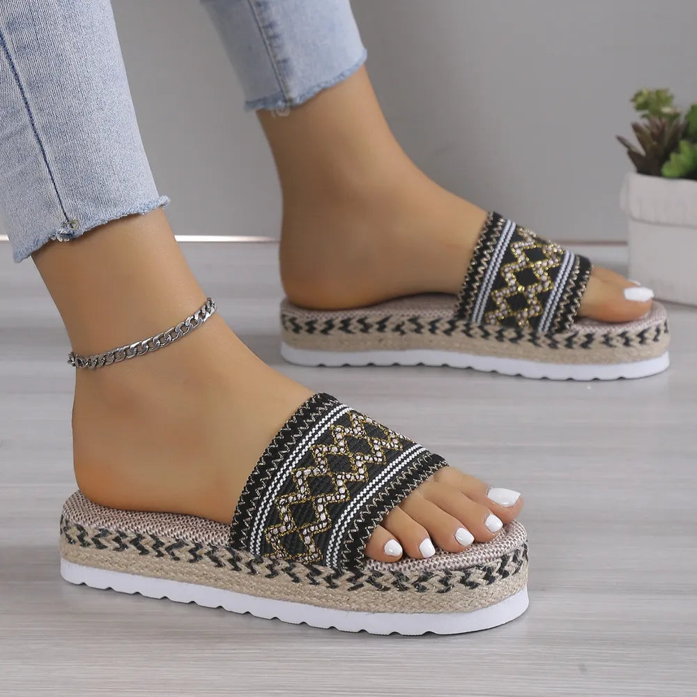 Embroidered platform espadrille slides in black with geometric pattern and rope detail.