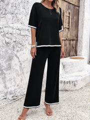 Black knit co-ord set with contrast white trim on sleeves and pants.
