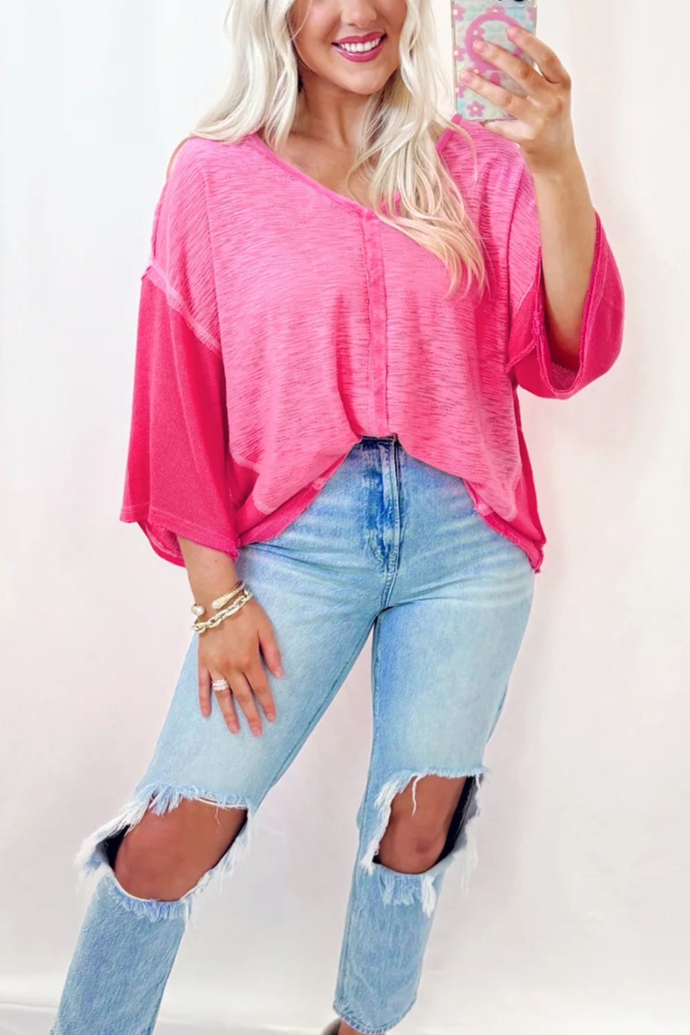 Hot pink contrast panel v-neck blouse with wide sleeves and raw hem jeans.