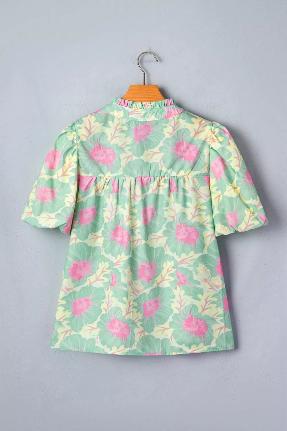 Pastel floral print polyester blouse with ruffled mock neck and puff sleeves.
