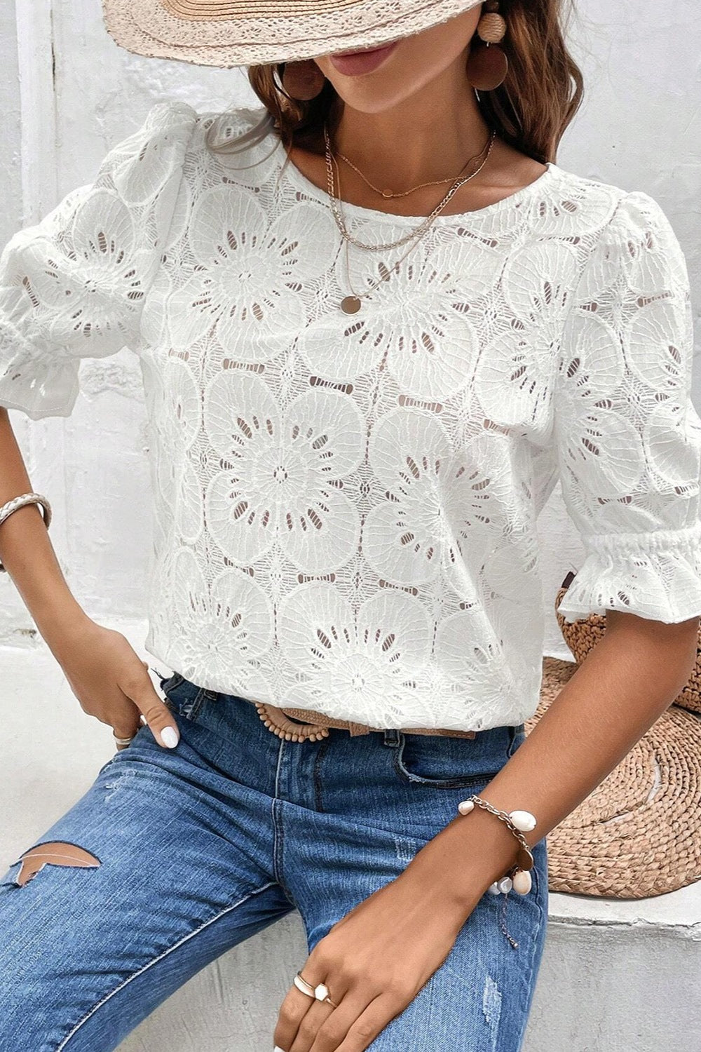 White eyelet blouse with floral pattern, puff sleeves, and ruffled cuffs.