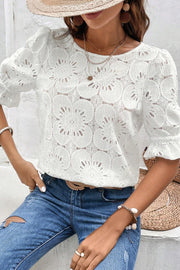 White eyelet blouse with floral pattern, puff sleeves, and ruffled cuffs.