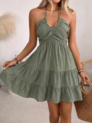 Olive green smocked halter mini dress with tiered skirt and button detail.