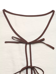 Beige tie-front two-piece ensemble with brown trim and bow details.