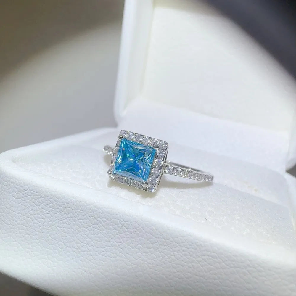 Silver ring with ice blue square halo center stone and clear accent stones.