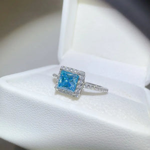 Silver ring with ice blue square halo center stone and clear accent stones.