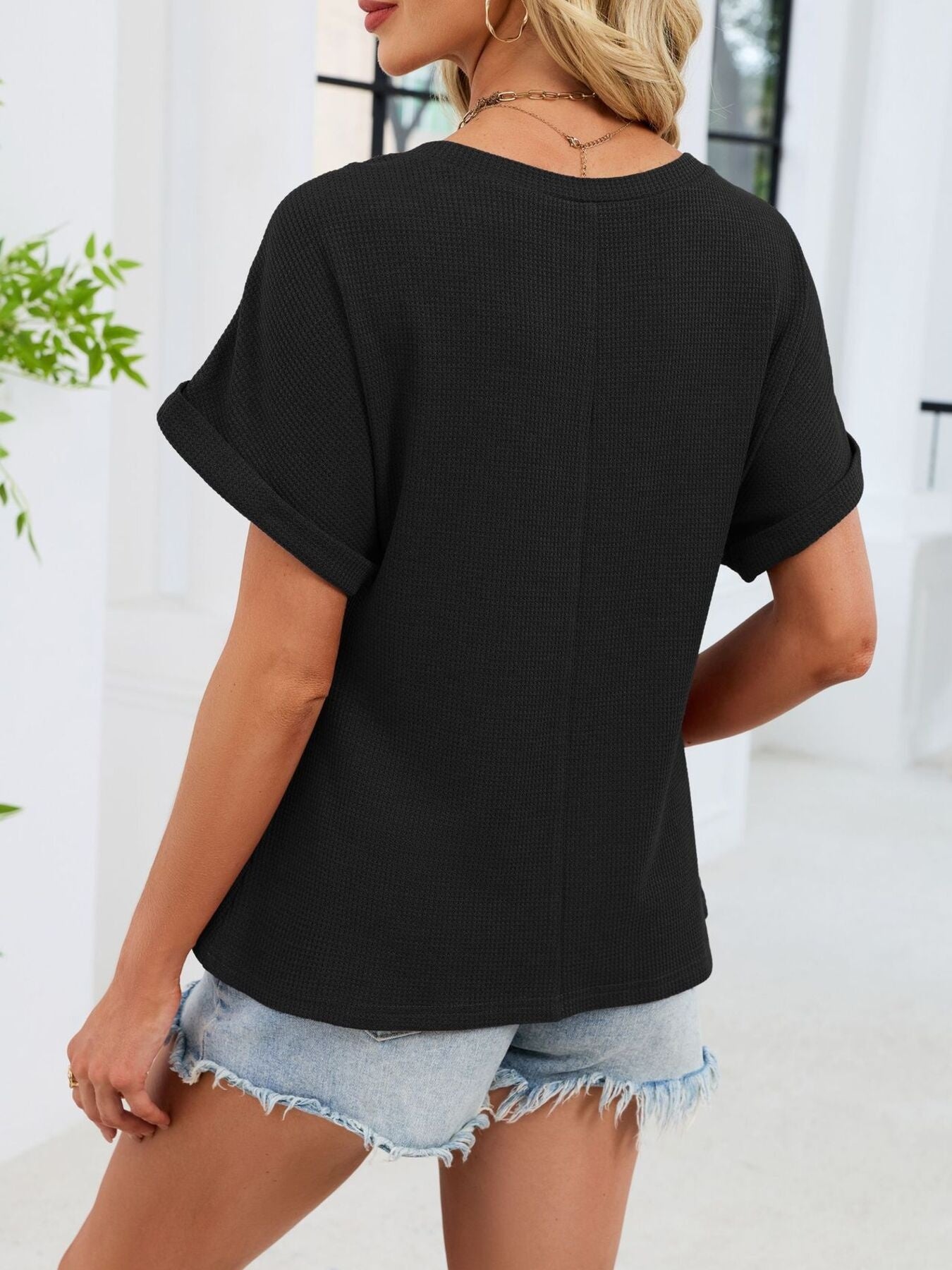 Black waffle knit t-shirt with cuffed short sleeves and a relaxed fit.