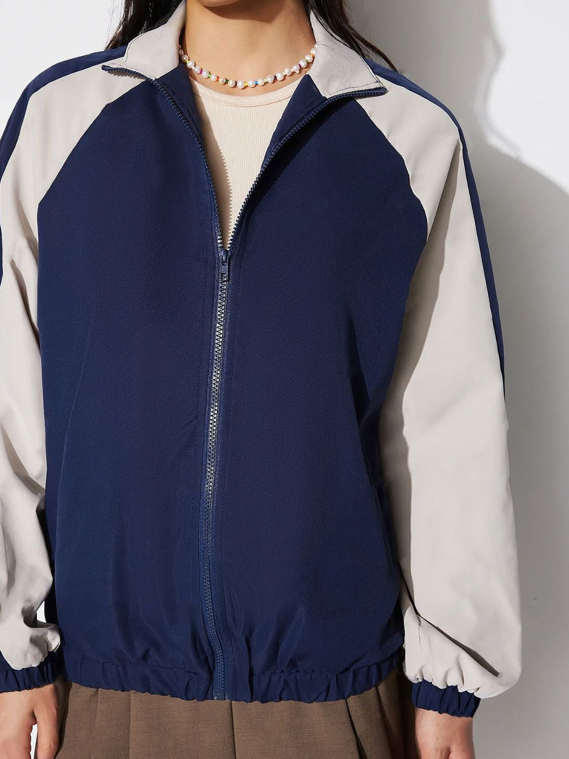Colorblock raglan sleeve bomber jacket in dark blue and light gray with a zip front.