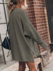 Oversized open-knit sweater dress in army green with side slits, styled casually.