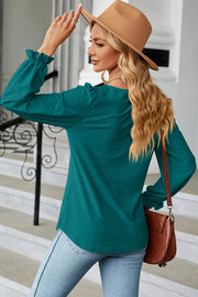Teal textured puff sleeve blouse with ruffled cuffs, styled with jeans and a hat.