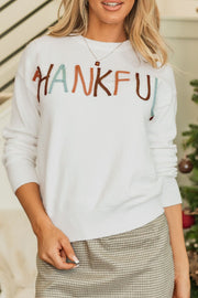 White drop shoulder sweater with "Thankful" embroidery in multi-color yarn.
