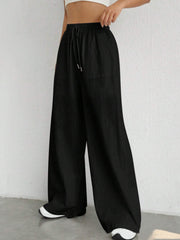 Black linen wide-leg drawstring trousers with pockets and a relaxed fit.