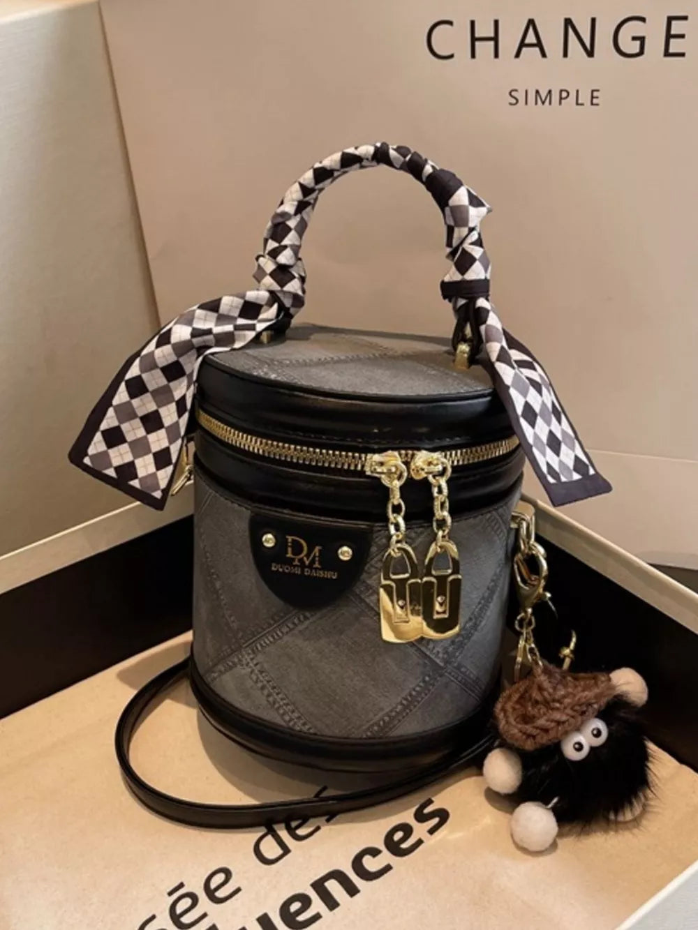 Quilted mini bucket bag in black with checkered scarf detail and fuzzy charm.