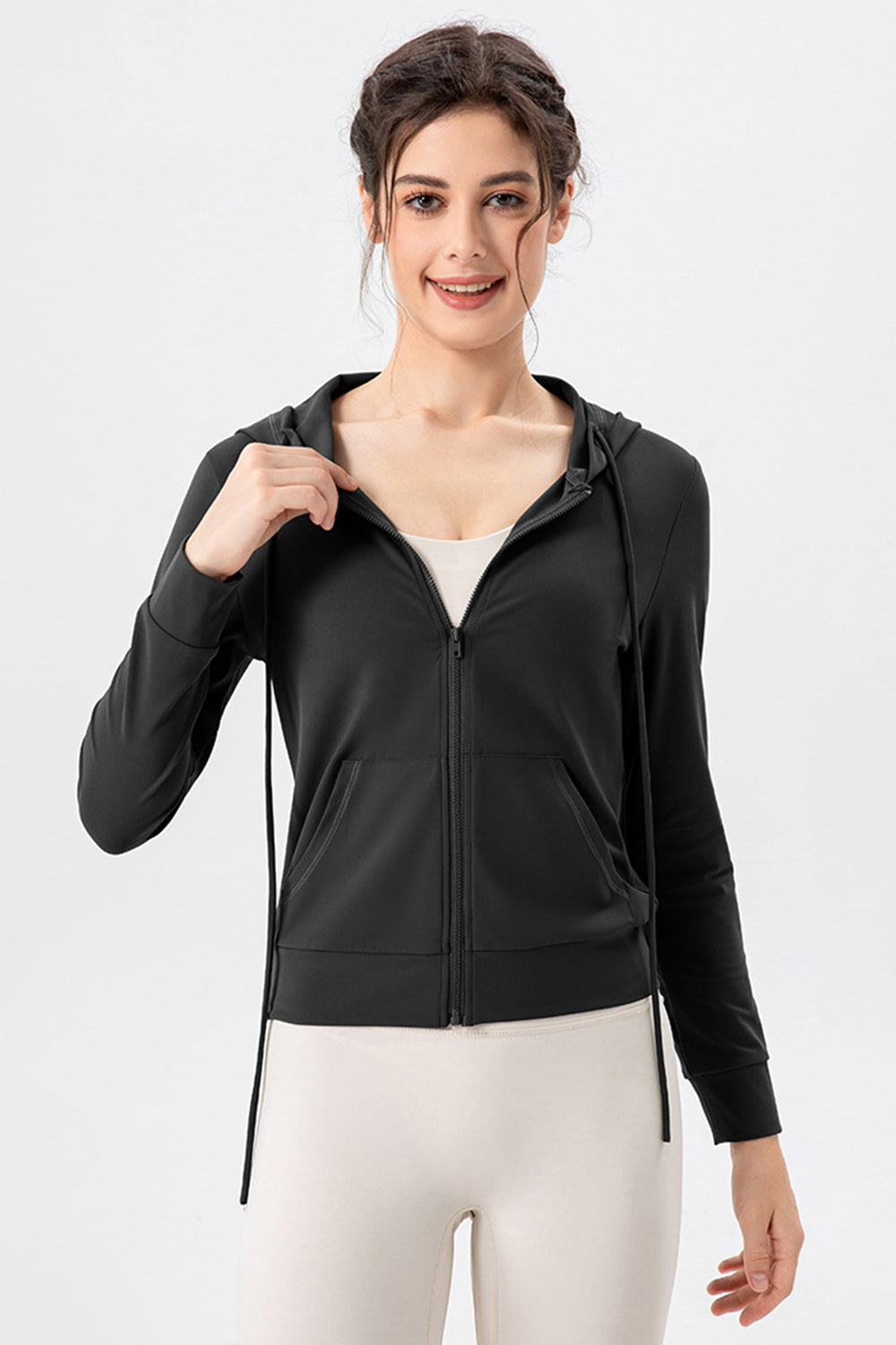 Black zip-up hoodie with drawstrings and pockets, styled with a white tank top.