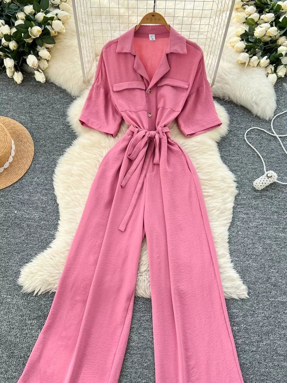 Pink belted wide-leg maternity jumpsuit with pockets and button front.