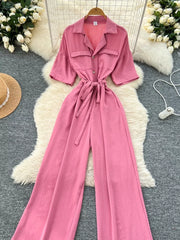 Pink belted wide-leg maternity jumpsuit with pockets and button front.