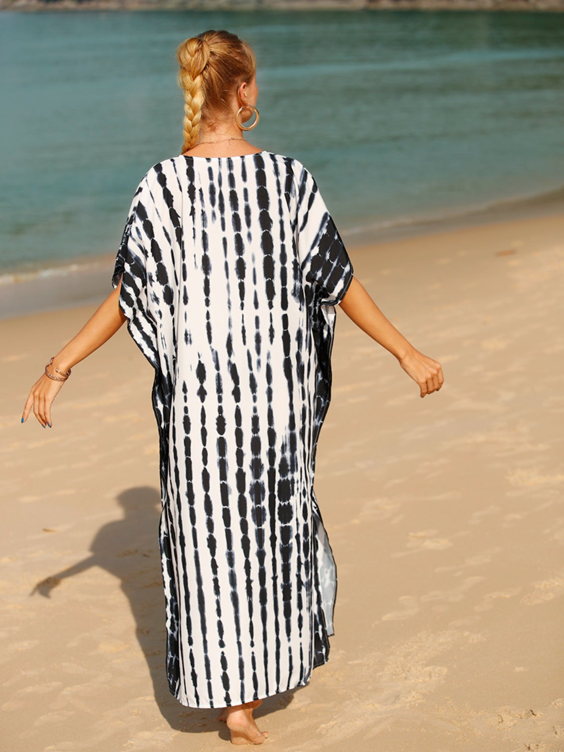 Black tie-dye maxi kaftan with vertical stripes and short sleeves, worn on the beach.