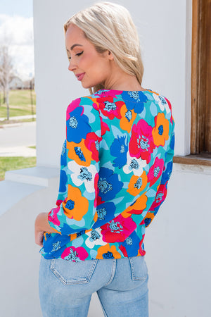 Painterly floral V-neck blouse in turquoise with pink, blue, and orange blossoms.
