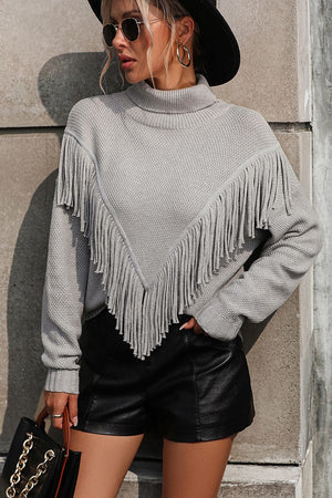 Light gray knit turtleneck sweater with chevron fringe detail and long sleeves.