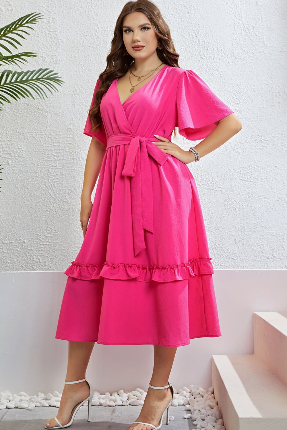 Hot pink wrap-front midi dress with flutter sleeves, belted waist, and tiered ruffled hem.