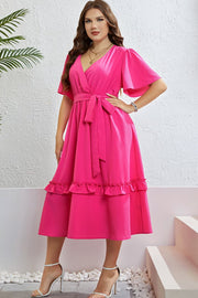 Hot pink wrap-front midi dress with flutter sleeves, belted waist, and tiered ruffled hem.