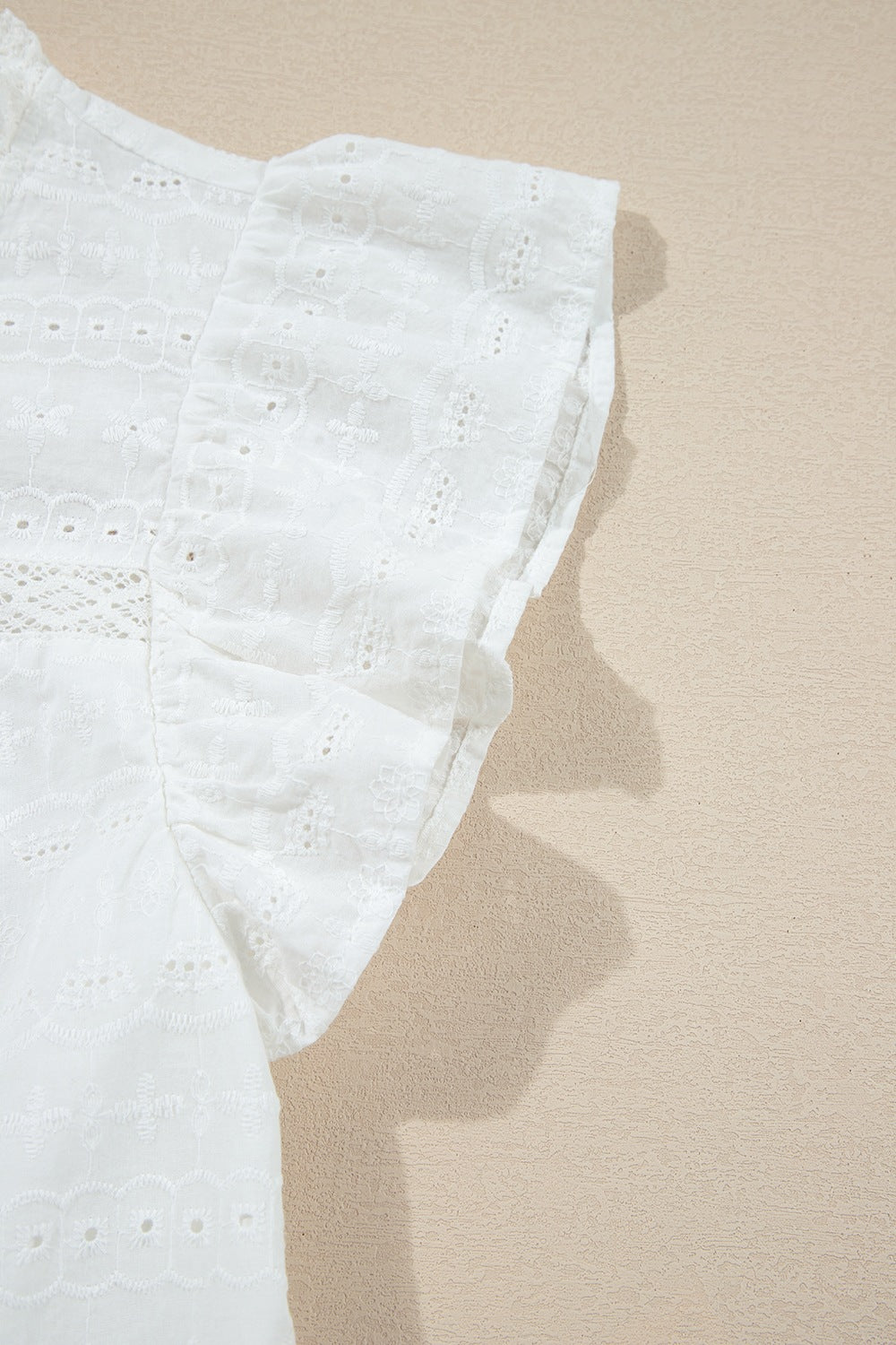 White eyelet yoke blouse with ruffle sleeves and intricate embroidery detail.