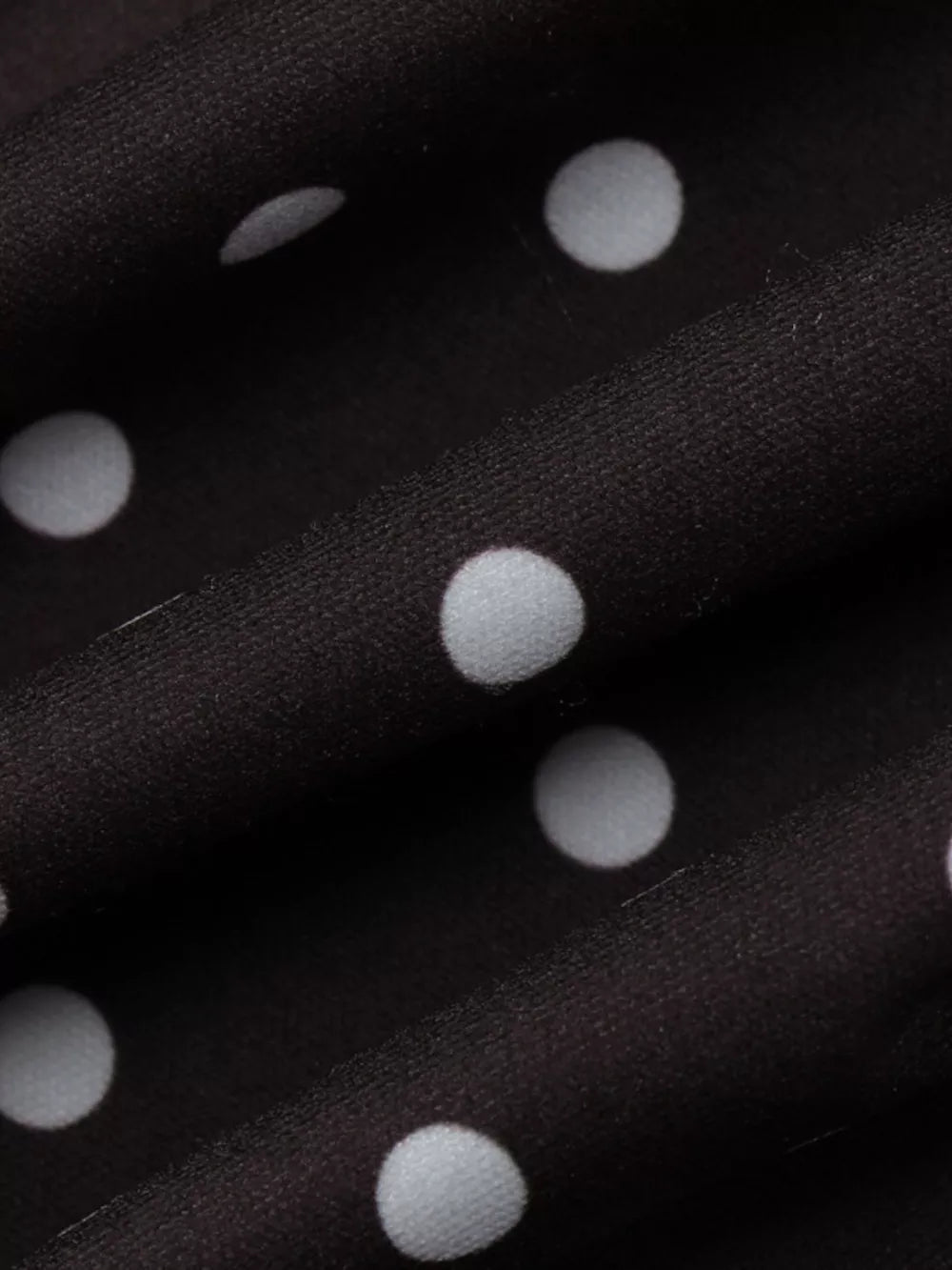 Chic polka dot mini dress in black with white dots, featuring a cut-out detail.
