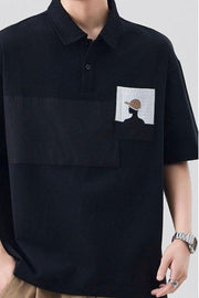Black polo shirt with embroidered pocket detail and contrasting chest panel.