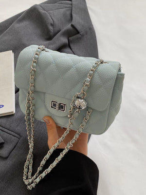 Blue quilted chain crossbody clutch bag with silver hardware and a turn-lock closure.