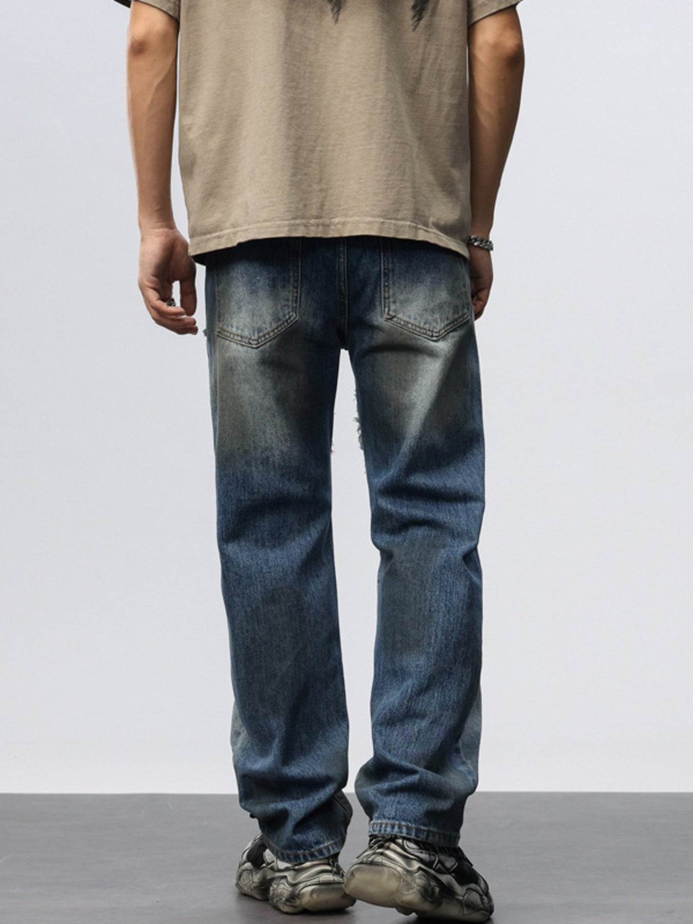Men's blue denim wide leg jeans with distressed details and frayed hem.