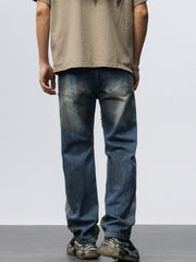 Men's blue denim wide leg jeans with distressed details and frayed hem.