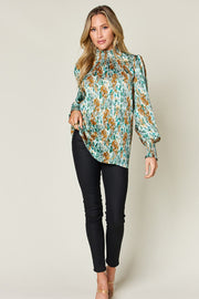 High neck abstract print blouse in green with smocked neckline and cuffs, long sleeves.