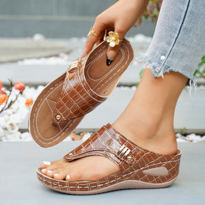 Brown crocodile-embossed wedge thong sandals with gold buckle detail.