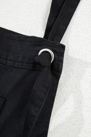 Black denim romper with adjustable straps and metal ring detail