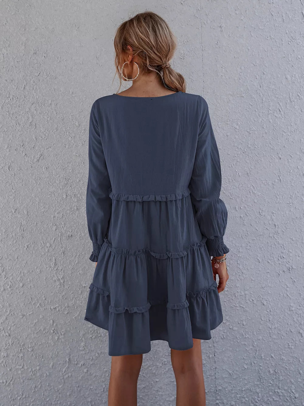 Navy blue ruffled mini dress with long sleeves and tiered skirt.
