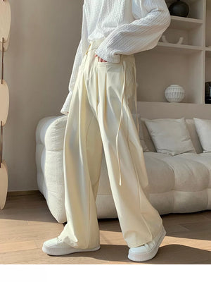 Men's wide-leg casual trousers in off-white with drawstring detail and pockets.