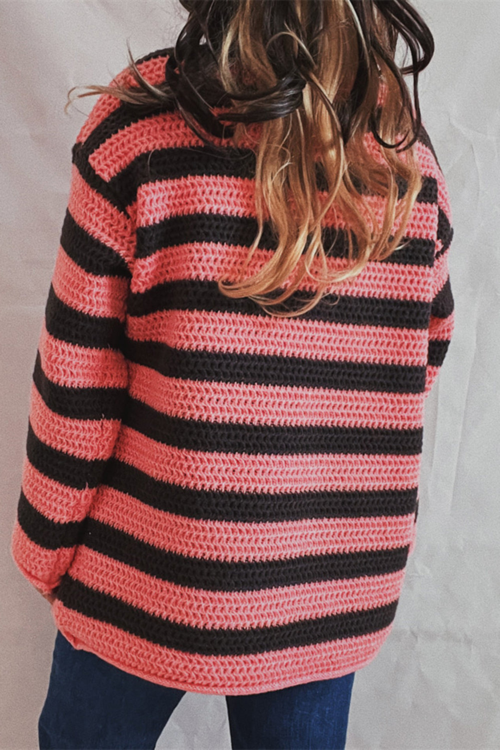 Pink and black striped knit sweater with boat neck and crochet texture.