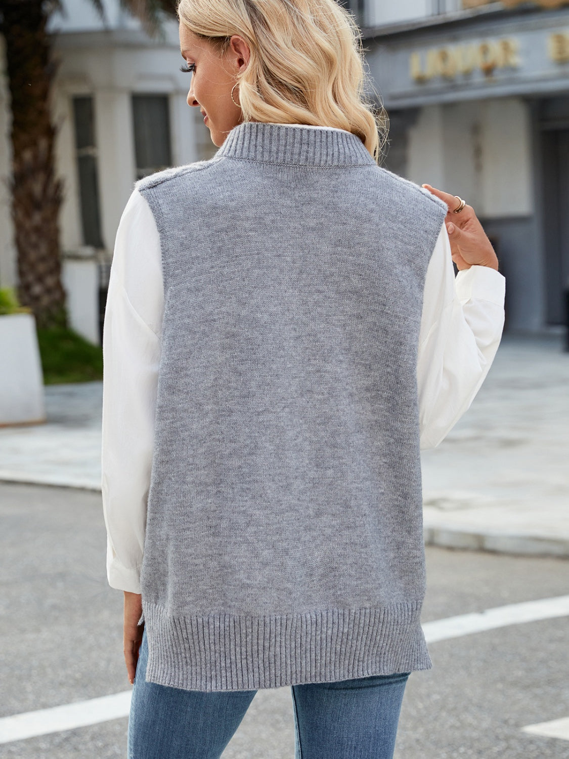 Gray cable knit sweater vest with ribbed collar and hem, worn over a white shirt.