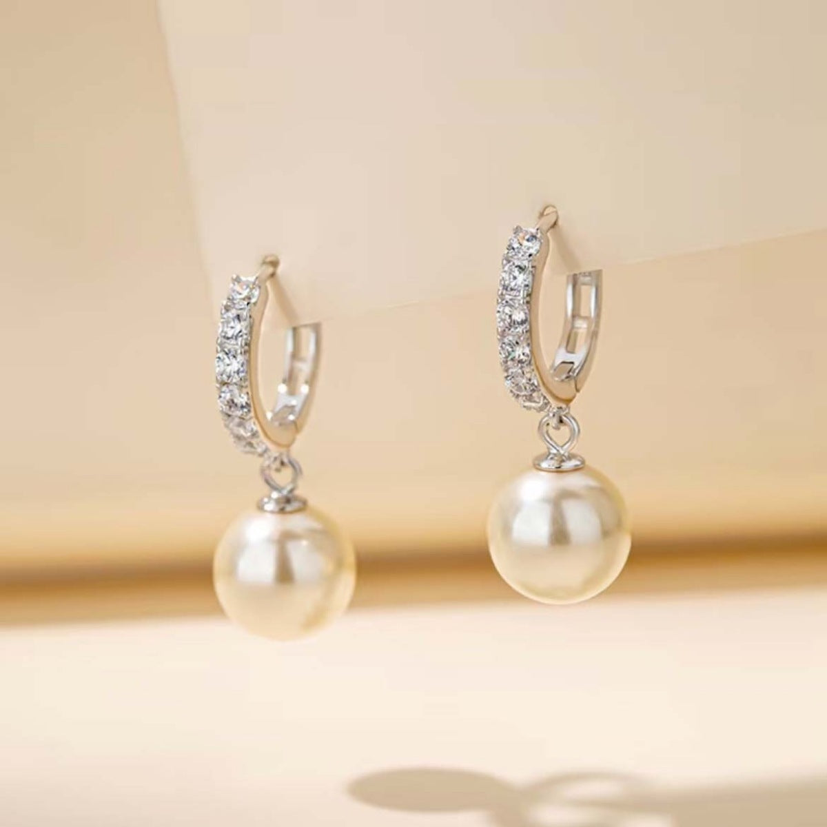 Elegant pearl drop hoop earrings with crystal accents.