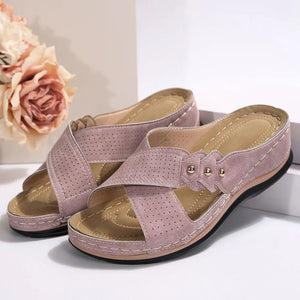 Perforated cross-strap comfort sandals in pink with decorative studs and cushioned footbed.