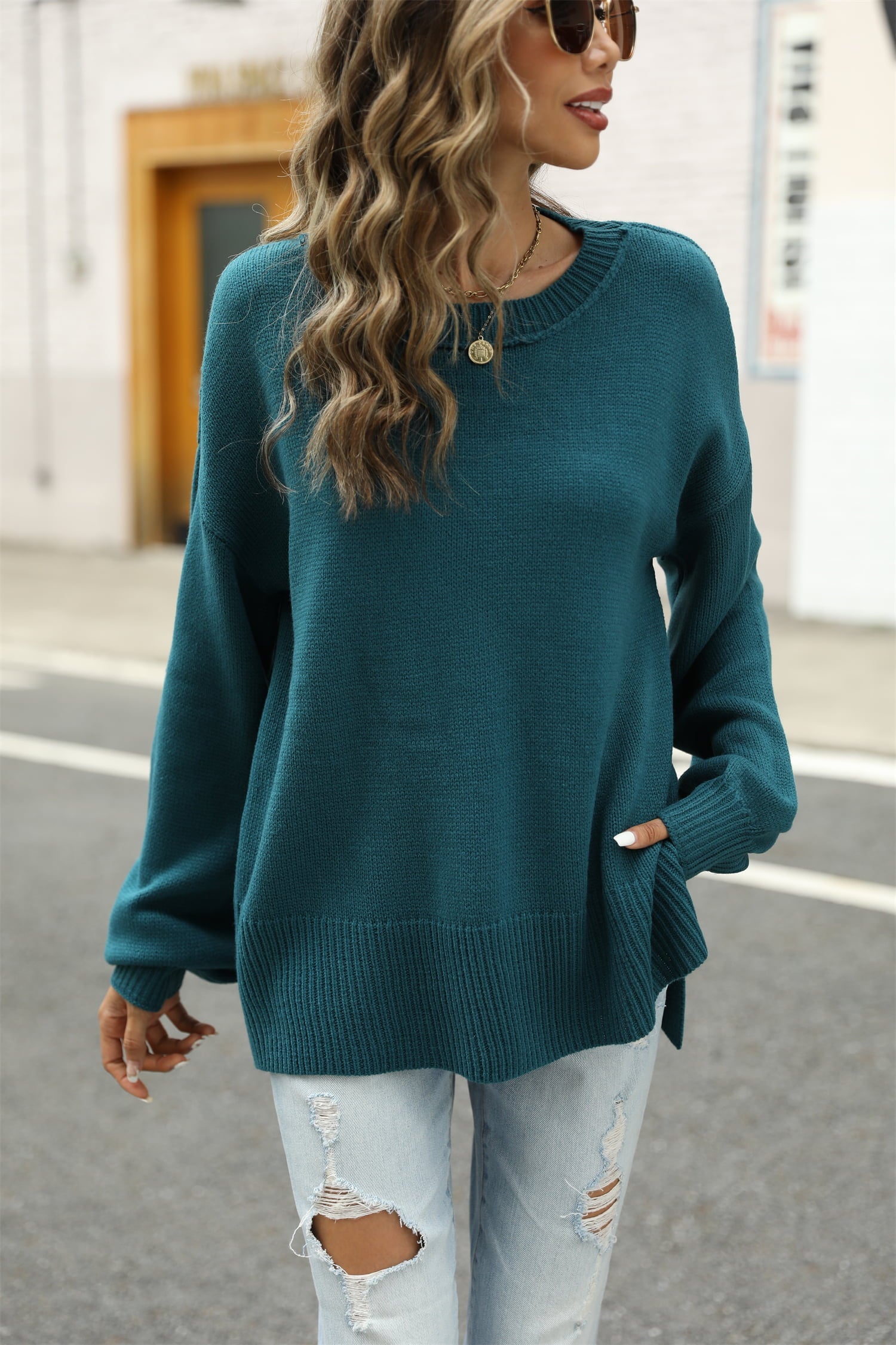 Turquoise knit pullover sweater with crew neck, long sleeves, and side slits.