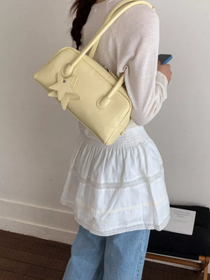 Yellow mini shoulder bag with star charm and double straps.