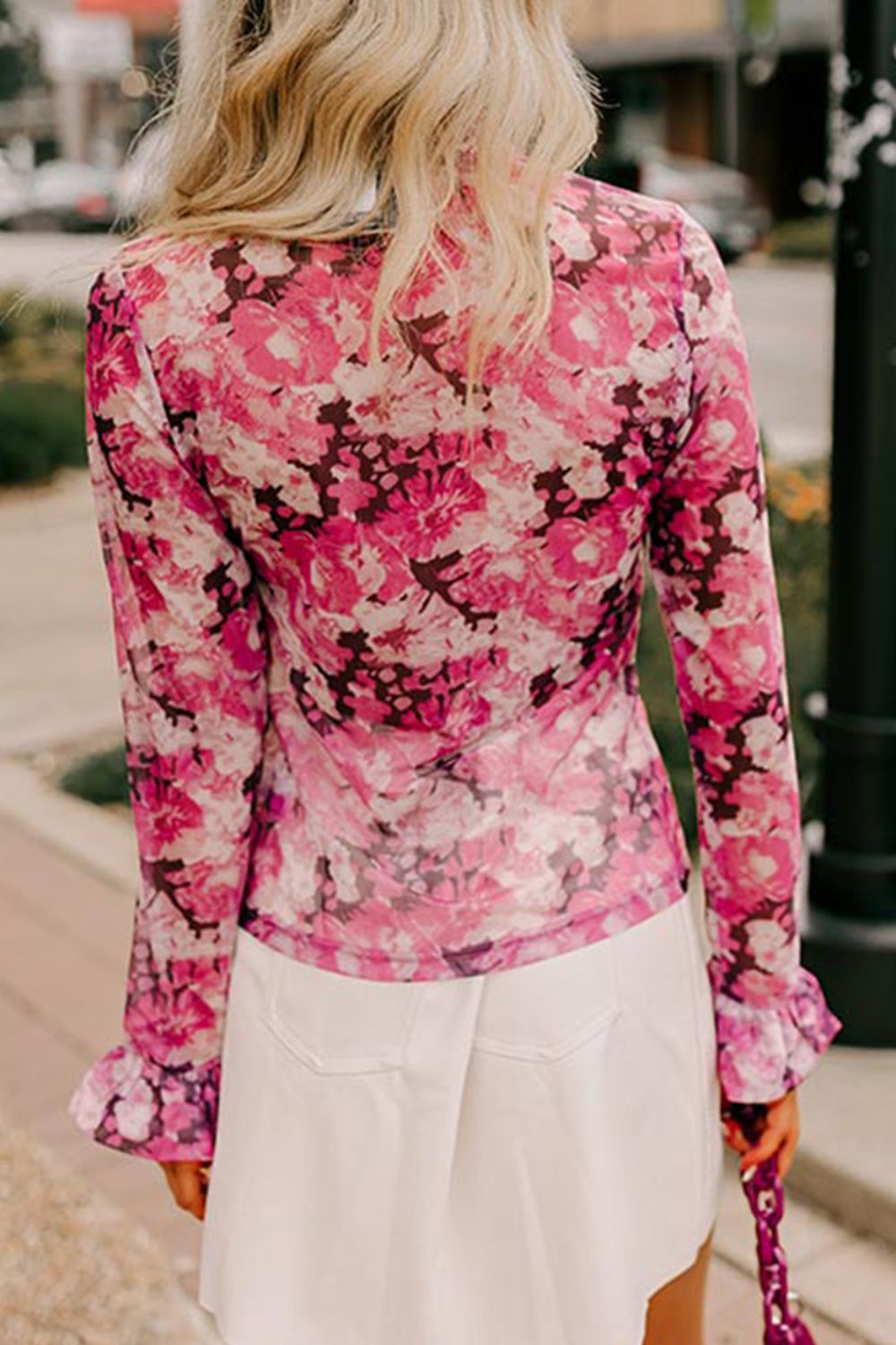 Sheer pink floral blouse with ruffle cuffs and long sleeves.