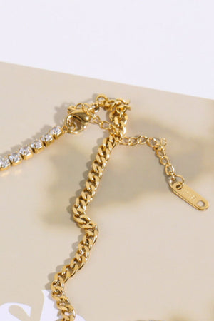 Gold curb chain necklace with a row of clear cubic zirconia stones and a lobster clasp closure.