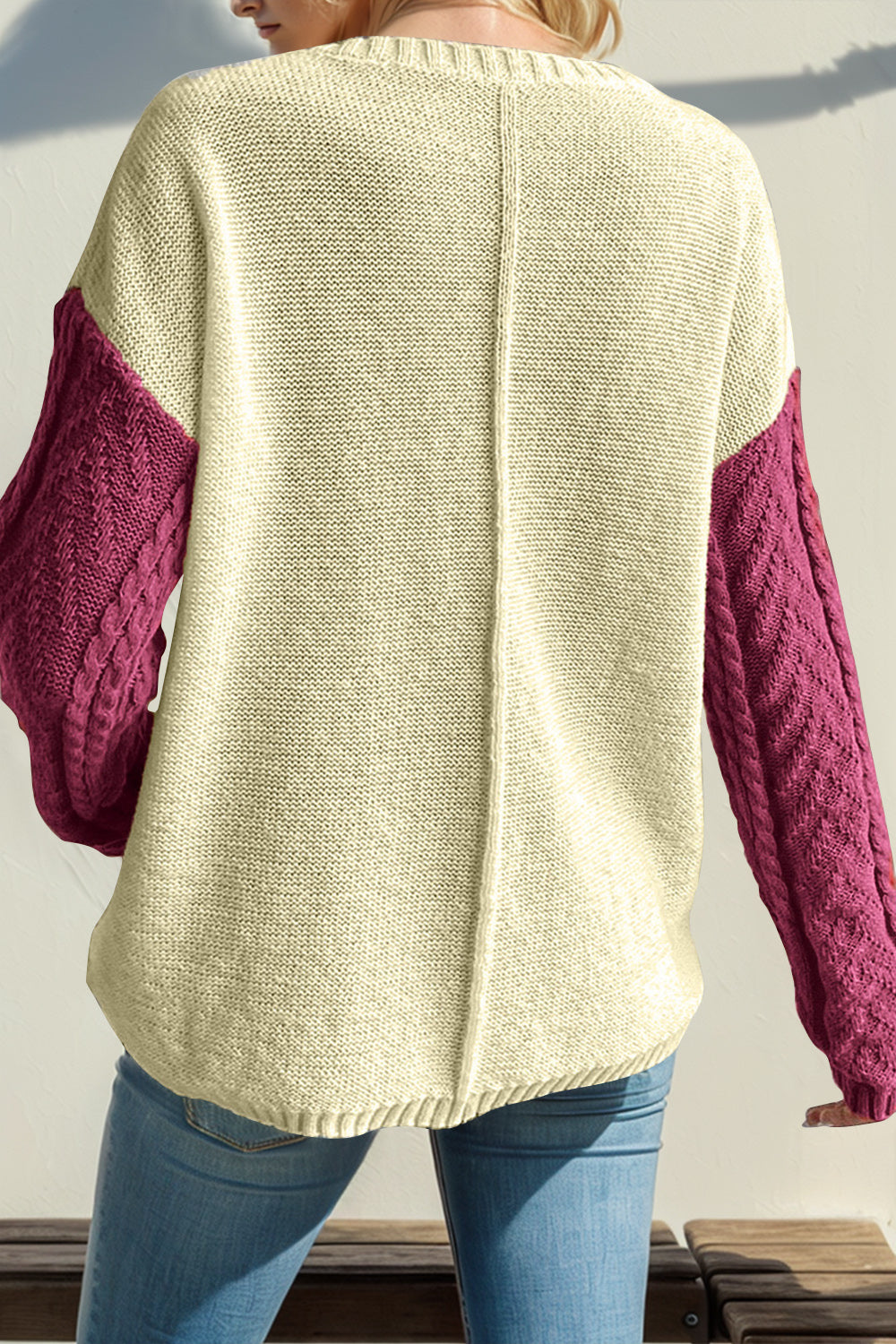 Colorblock cable knit sweater with red-violet sleeves and cream body.