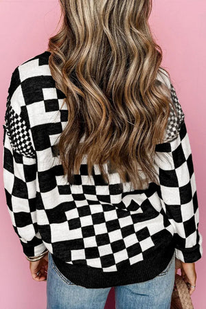 Black and white geometric checkerboard knit pullover sweater with crew neck.