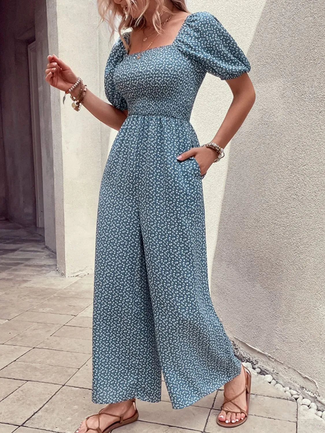 Smocked bodice floral wide-leg jumpsuit in dusty blue with puff sleeves and square neckline.