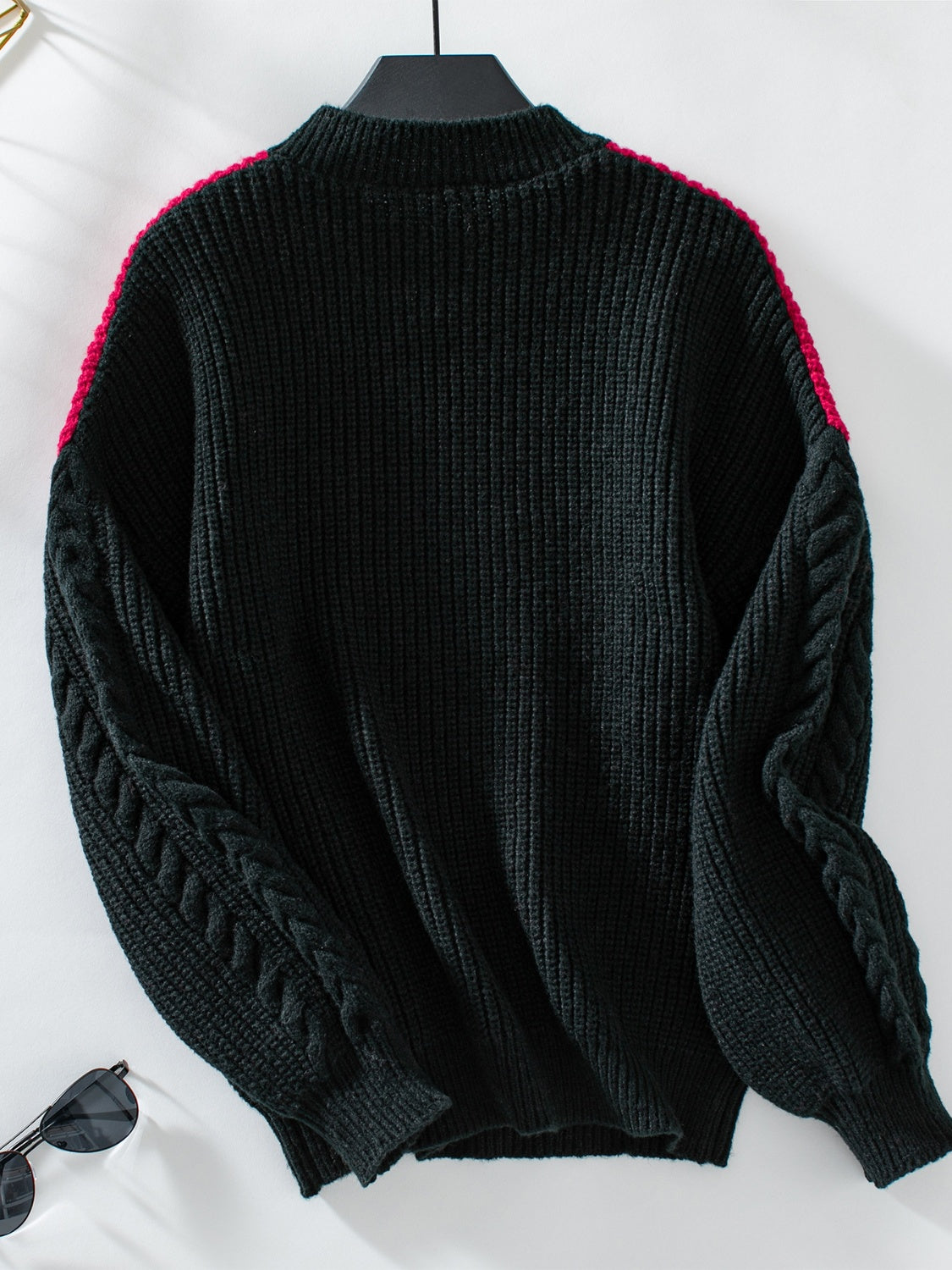 Black cable knit sweater with contrast pink shoulder detail and mock neck.